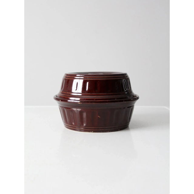 This is a vintage stoneware casserole dish. The brown glazed ceramic cookware features a ribbed design and lid with inset...