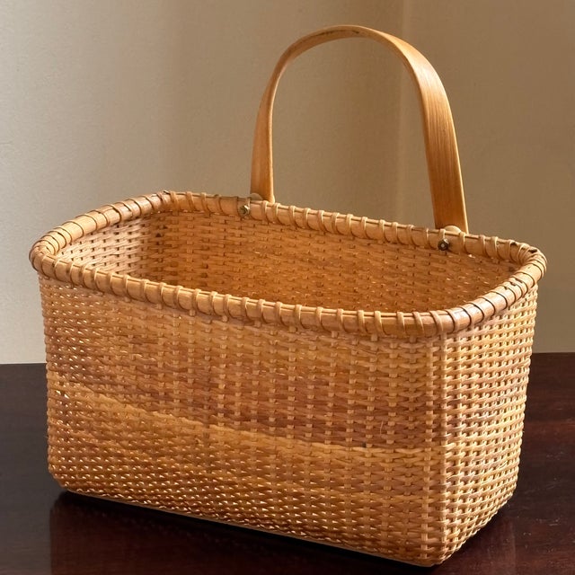 A beautiful handwoven Nantucket style basket from the late 20th century. This basket features a solid wood bottom in the...