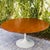 Early Saarinen Tulip dining table by Knoll c. 1960s, 60" round. The surface features a repeating walnut woodgrain pattern...
