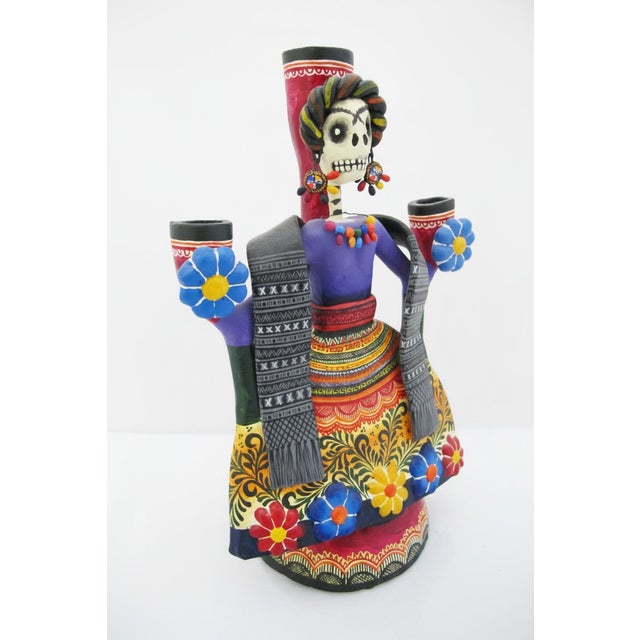 Day of the Dead skeleton styled as a tribute to the iconic Frida Kahlo. This striking candelabra was created by master...