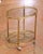 Crafted in France circa 1960, this elegant mid-century brass bar cart features a refined neoclassical design with a light...
