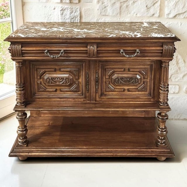 Richly carved in walnut and crowned with a beautifully veined marble top, this antique French buffet embodies the...