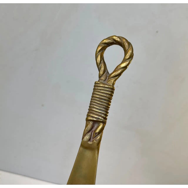 Elegant long shoe horn in brass decorated with draped detailing. It can be wall hung in your entrance. It was handmade in...