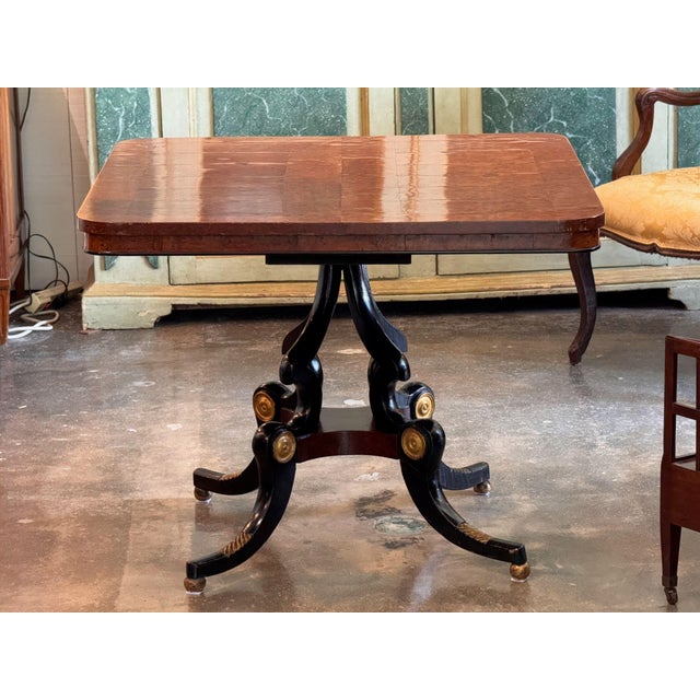 An English Regency table, the square top veneered in richly figured burled walnut with rounded corners and a fine ebonized...
