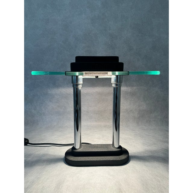 The “Penta” lamp by Robert Sonneman features a clean, architectural silhouette with two chrome supports and a thick glass...