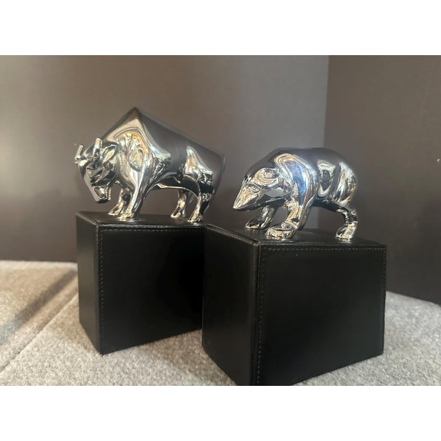 Vintage polished, heavy cast chromed metal bull and bear pair of bookends are mounted on leather clad, heavy base. Also...