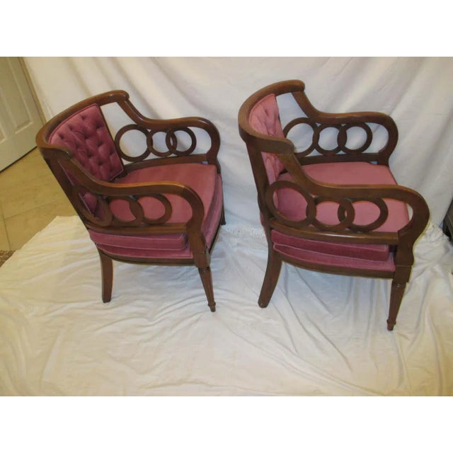 Pair of plum velvet upholstered barrel backed Hollywood Regency circle armchairs. Chairs are dark stained and have...
