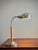 A striking vintage 1970s adjustable desk lamp combining warm orange color with cool brushed chrome for a quintessentially...