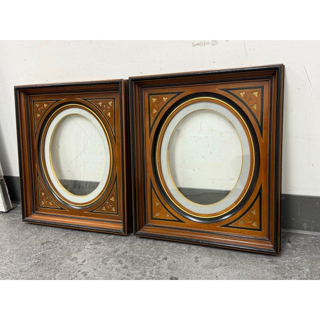 Design Plus Gallery presents a Pair of Circa 1895 Victorian Wood + Oval 18 Karat Gold Picture Frames. Presenting a...