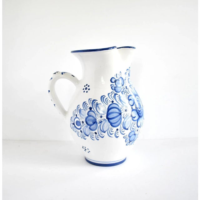 A vintage Czech ceramic pottery pitcher by Modra Slav Keramika, hand-painted with blue and white flowers in a folk design....