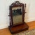 A beautifully detailed vintage tabletop vanity mirror in a rich mahogany finish, featuring turned side supports, a carved...