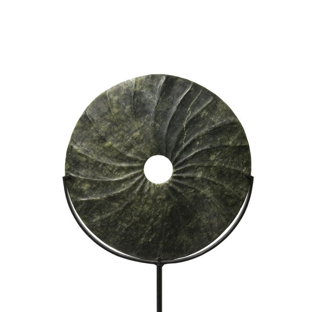 This striking jade bi disc, a symbol of ancient craftsmanship, stands poised on a sleek black metal stand, its circular...