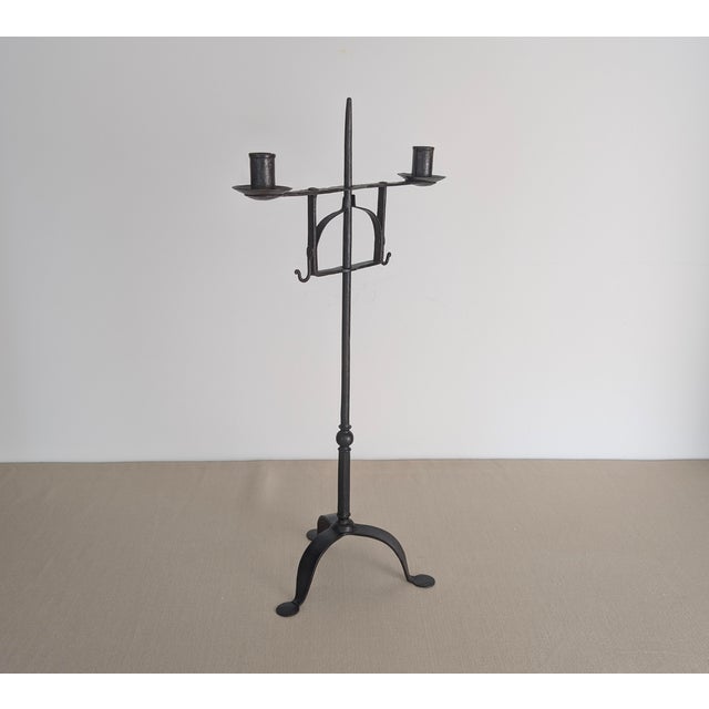 An unusual antique hand-wrought iron standing candleholder, dating to the late 18th. The tall central shaft is fitted with...