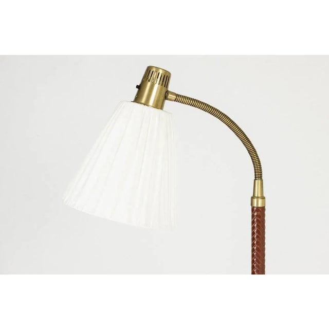Elegant floor lamp by Hans Bergström, made from brass and dressed in wreathed red leather. Flexible neck. This piece has...