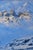 This oil painting depicts a majestic castle perched on a rugged mountain pass, surrounded by snow-covered peaks and a...