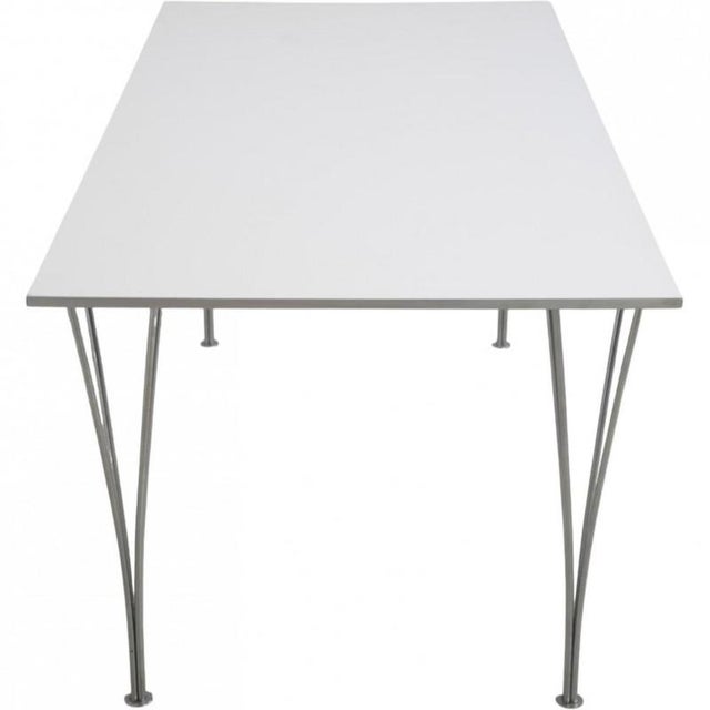 Piet Hein square dining table with a white laminated table top and an edge of aluminium. The table has a steel frame and...