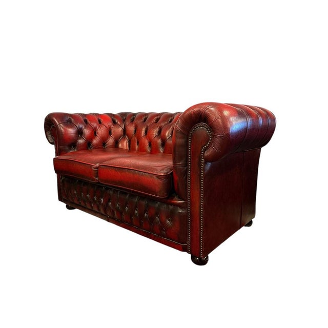 Classic English two-seater Chesterfield from Winchester in rich oxblood leather with deep button-tufting and rolled arms....