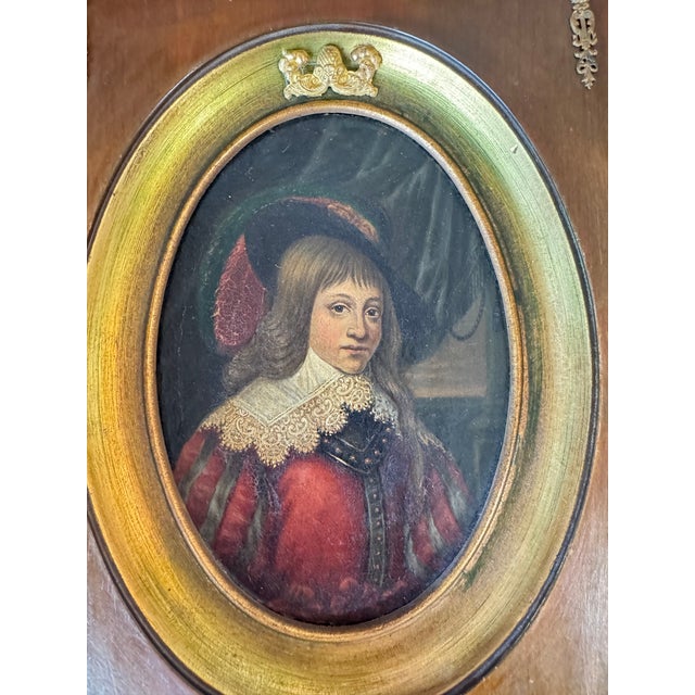 A captivating small cabinet portrait of a young boy in 17th-century cavalier dress — plumed hat, flowing hair, and an...