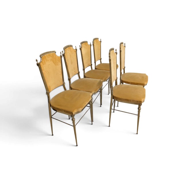 A refined set of six vintage dining chairs featuring an elegant brass frame and luxurious mustard-colored velvet...