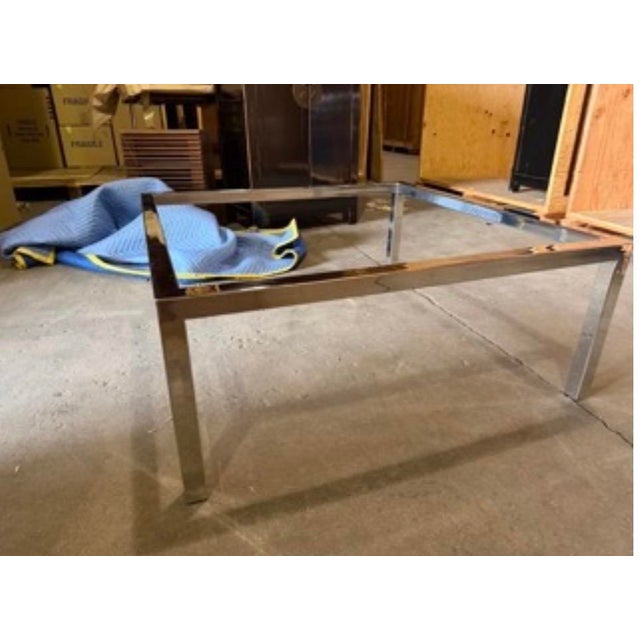 Elegant vintage modernist coffee table featuring a 38-inch square glass top resting on a minimalist chrome-plated steel...