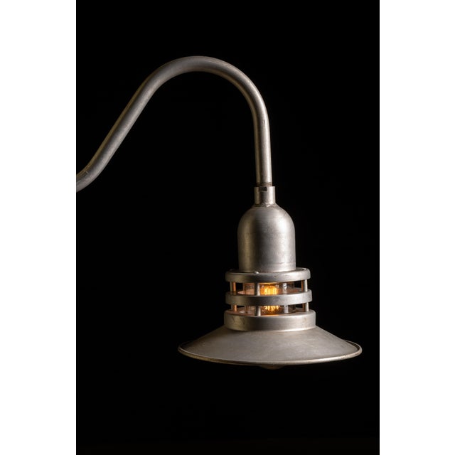 This vintage industrial wall lamp harkens back to the atomic age. This gooseneck aluminum piping leads to a lamp housing...