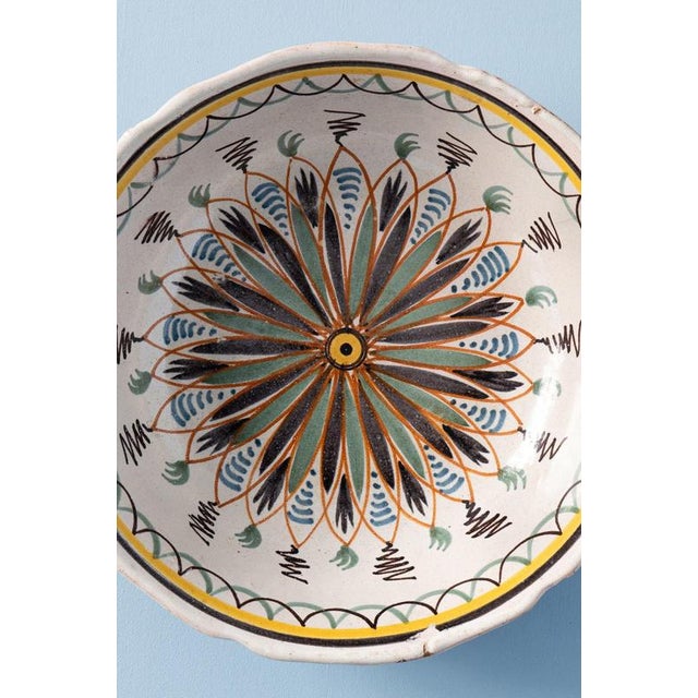 An early 19th-century French faience large bowl from Nevers, decorated with a central rosette surrounded by painterly...