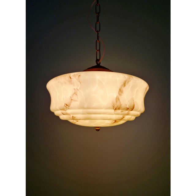 Art Deco pendant light in marbled opaline glass, pale yellow with brown veins, brass mount, 1920s-30s. The pendant light...