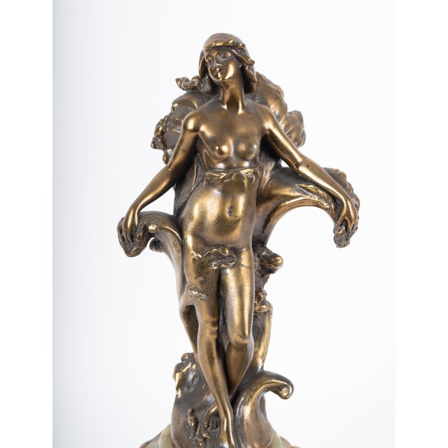 An exceptional French Art Nouveau gilt bronze mantel clock featuring a graceful female figure signed “Ferrand,” resting...