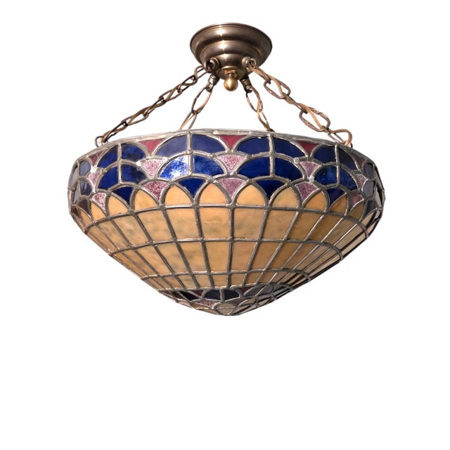 Original period colorful hand‑crafted stained glass semi flush‑mount fixture with a vibrant geometric dome in amber,...