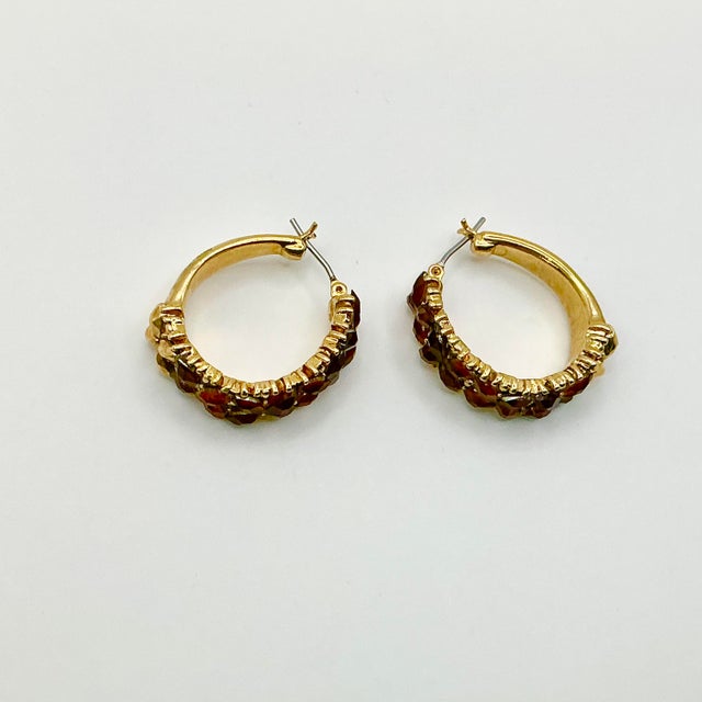 A pair of pierced gold tone hoop earrings from the 1980s. They are enhanced with small marquise shaped Baltic Amber...