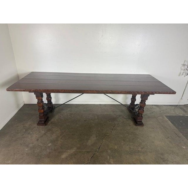 A substantial and architecturally grounded dining table executed in the Spanish Revival tradition, featuring a thick plank...