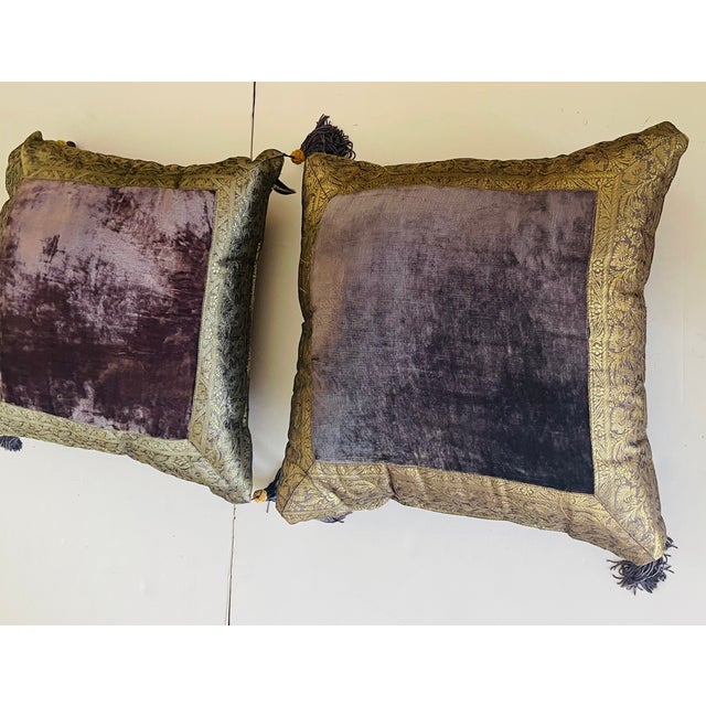 Richly decorated pair of eggplant velvet pillows with brocade gold wide trim and brocade back, with tassels.