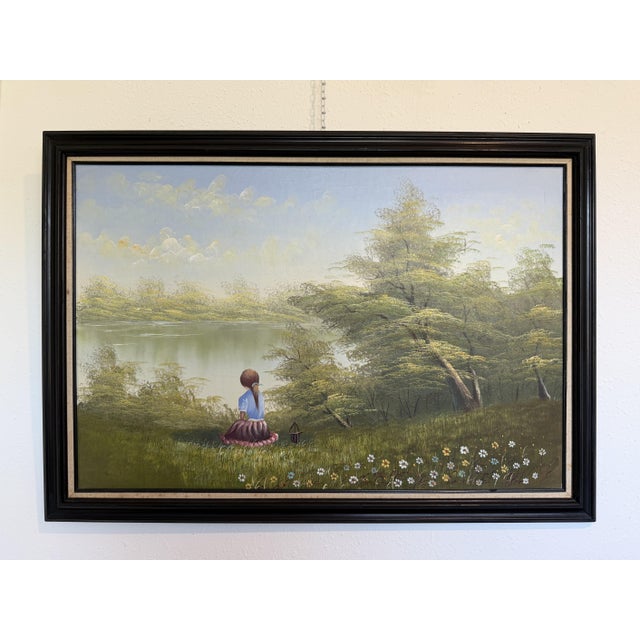 This atmospheric vintage oil painting depicts a young girl seated quietly on a grassy hillside, gazing across a calm lake...
