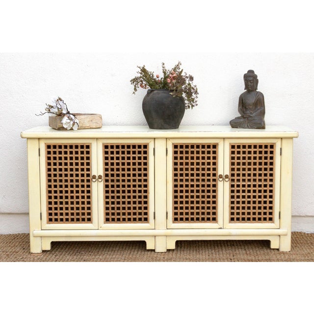 A riddle of light and shadow, crafted in wood and cream. This striking sideboard commands a presence, measuring a generous...