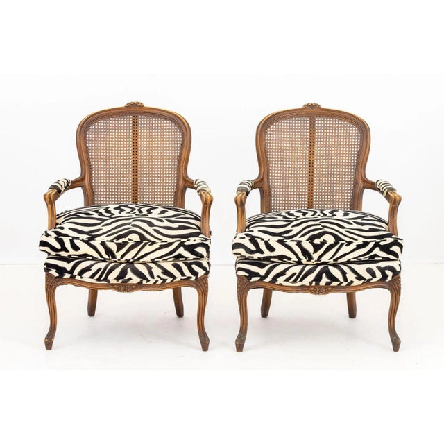 Pair of French Provincial Style Zebra Upholstered Armchairs, walnut frame with floral crest above a caned back and black...