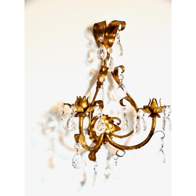 A lovely Mid 20th-Century Italian tole double arm candle sconce with prism cut crystals. It has a decorative center floral...