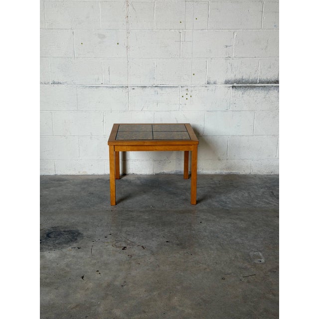 This striking accent table showcases an inset tile top with golden abstract patterns. Clean lines and slender legs define...