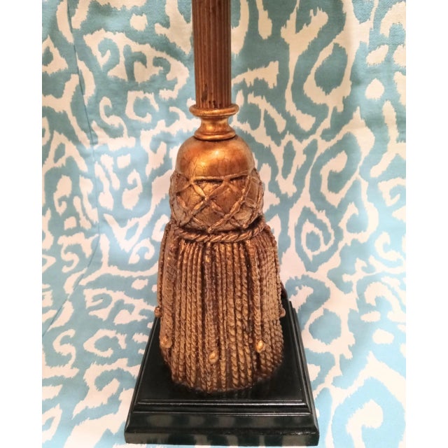 A tall vintage gold leaf tassel design table lamp with a wicker shade. The lamp has a beautiful elegant tassel designed...