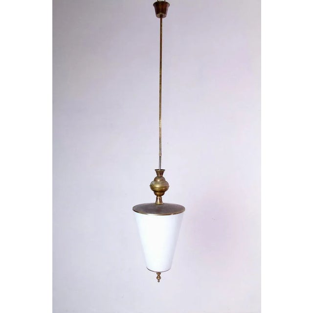 A 1950s sleek pendant in brass with an original opaline glass shade. The brass is lacquered in the pics. The total height...