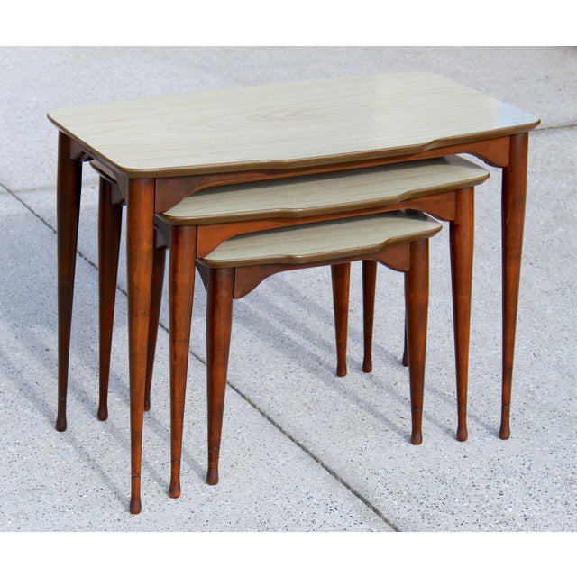 Discover a unique and hard-to-find set of vintage mid-century modern nesting tables, complete with neutral beige tops and...