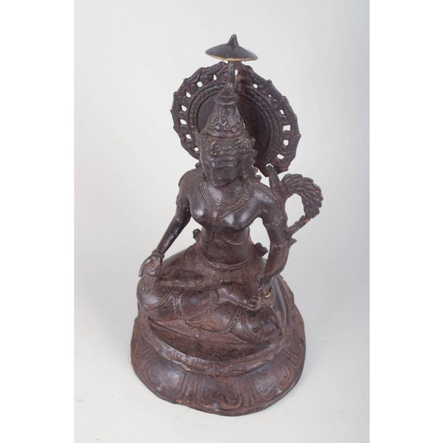 Buddhist bronze figure. Seated Buddhist figure executed in patinated bronze with an elaborate headdress, pierced halo and...