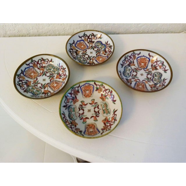 Lovely set of four mid-century brass encased decorative porcelain bowls featuring a hand-painted ornate motif on white...