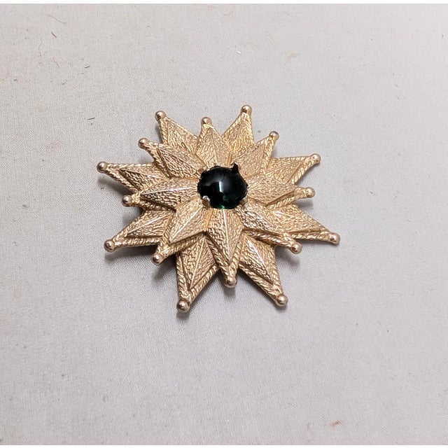 1960s goldtone medallion or flower with cabochon faux-emerald center brooch with security clasp and a loop so it can be...