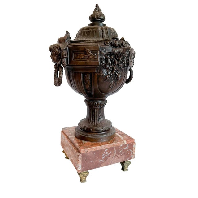 Showcasing a beautiful aged patina, this 19th-century cast bronze lidded urn on a marble base features intricate details...