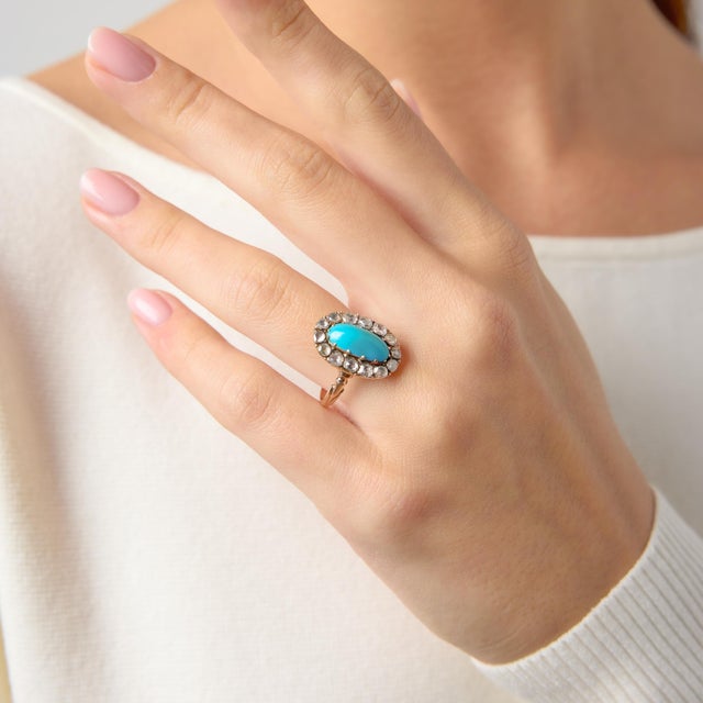 This enchanting Victorian cluster ring showcases a vibrant cabochon turquoise, glowing with a rich, sky-blue hue that...