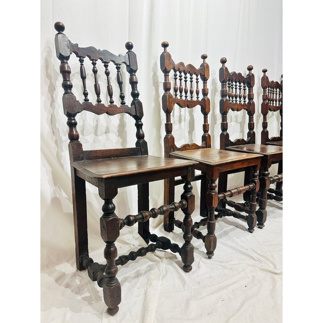 A richly patinated set of four early provincial walnut dining chairs featuring beautifully hand-turned spindle backs,...