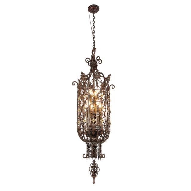 Spanish Revival style extra large pendant light with a wrought bronze scrolled cage and finial. It features floral brass...