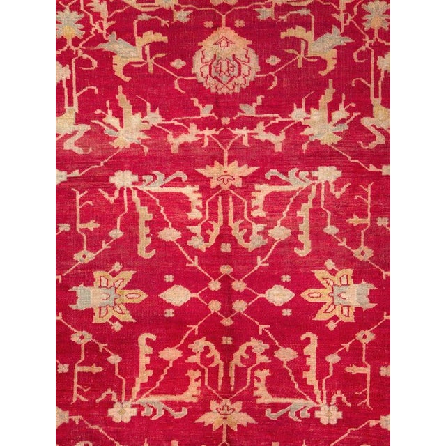 An antique Turkish Oushak room size carpet in square format handmade during the early 20th century with a bright red field...
