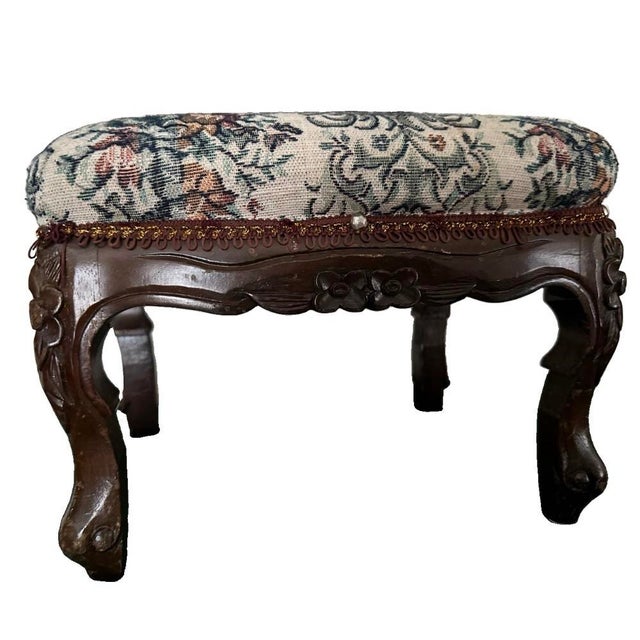 Vintage early-mid 20th Century footstool. Frame is mahogany wood with ornate carvings and cabriole legs. Top is cushioned...