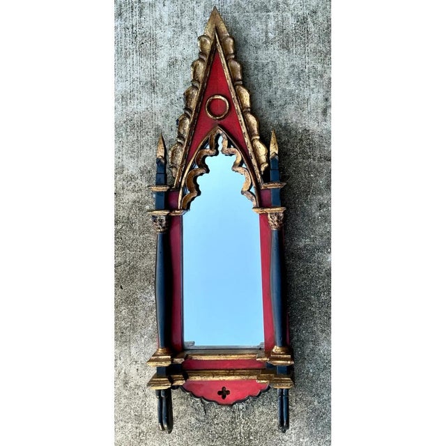 This mirror presents a dramatic, architecturally inspired silhouette drawn directly from Gothic ecclesiastical design, its...